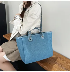 Blue woven large capacity chain tote bag shown on a model sitting on a wooden bench