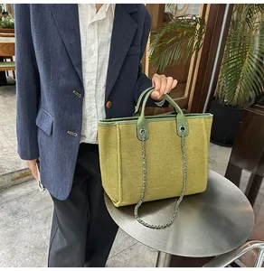 Large olive green textured canvas tote bag featuring leather trim and a silver-tone chain strap