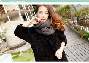 Detailed view of grey thick knit infinity scarf on a model with a black textured coat