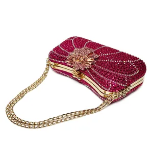 Close-up of fuchsia rhinestone evening clutch with gold flower clasp and long chain.