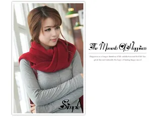 Lifestyle shot of a woman wearing a thick red knitted winter scarf in cozy light