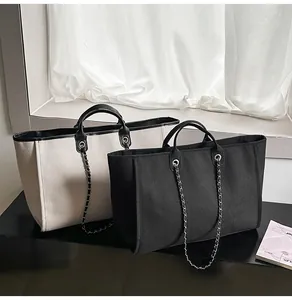Close-up detail shot of large black and beige canvas tote bags with silver chain straps