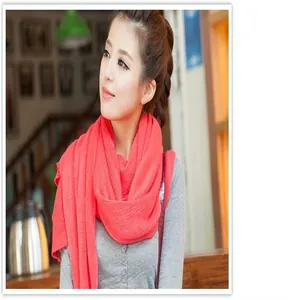 Detail view of a model wearing a bright coral red knitted winter scarf for warmth
