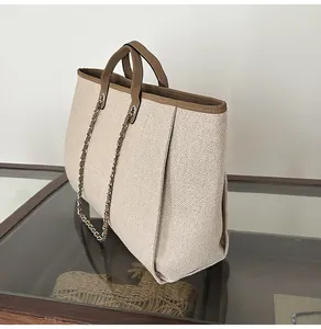 Side view of a large capacity beige woven tote bag with brown trim and chain strap.