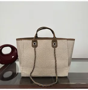 Front view of large canvas tote bag with brown leather trim and elegant silver chain strap