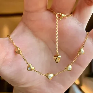 Close-up of a gold necklace featuring five sparkling heart-shaped diamond pendants.