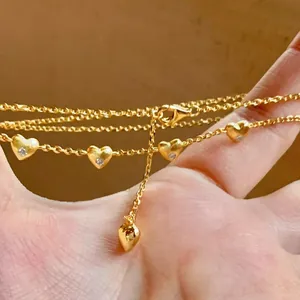 Detailed close-up view of a gold necklace featuring five delicate heart pendants with diamonds