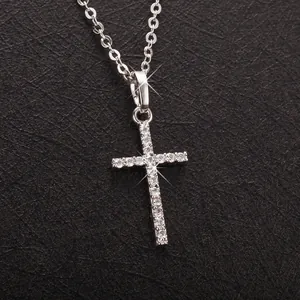 Close-up of a sparkling silver rhinestone cross pendant necklace on dark background