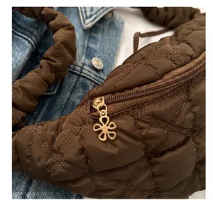 Close-up of brown quilted puffer bag featuring a gold flower-shaped zipper pull detail.
