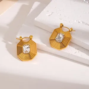 Close-up detail of geometric gold stainless steel earrings with sparkling crystal