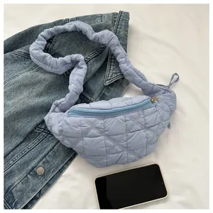 Detail of light blue quilted chest bag with ruffled strap and gold zipper