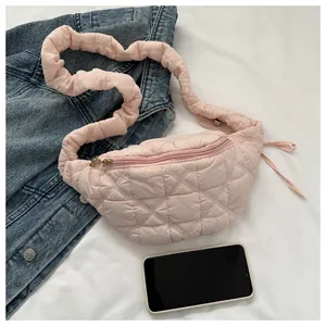 Detail of pink quilted crossbody bag with stylish ruffled strap and denim backdrop