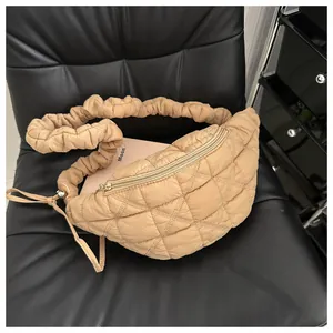 Quilted beige chest bag with a ruffled strap shown on a black textured chair seat
