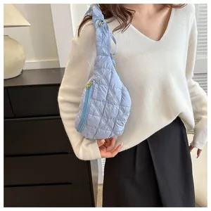 Detail of stylish light blue quilted chest bag worn with white sweater and skirt