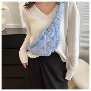 Detailed view of a light blue quilted chest bag featuring a floral zipper charm.