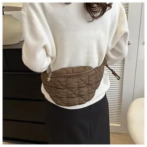 Woman wearing a brown quilted waist bag over a white sweater in a modern interior.