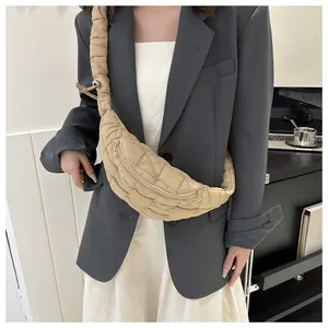 Close-up of stylish beige quilted crescent chest bag worn with professional grey blazer