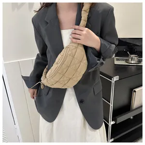 Fashionable beige quilted chest bag worn over a grey blazer for a modern and stylish look.