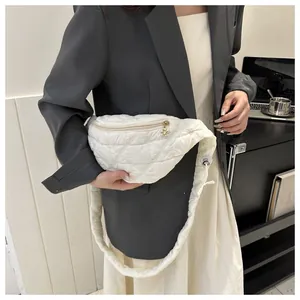 Close-up of a white quilted fanny pack with flower zipper charm worn over a blazer