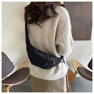 Fashionable black quilted crossbody chest bag worn with a chunky cream knit sweater