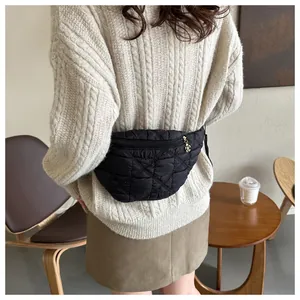 Detail view of a stylish black quilted fanny pack worn with a cozy beige cable-knit sweater.