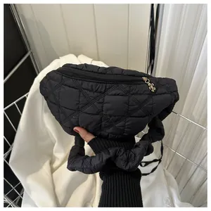 Close-up of a stylish black quilted chest bag with a gold flower zipper charm detail.