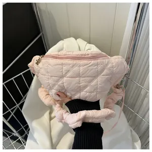 Close-up view of a pink quilted chest bag with diamond pattern and flower charm detail