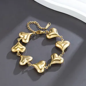 Close-up detail of a polished gold stainless steel bracelet with puffed heart links.