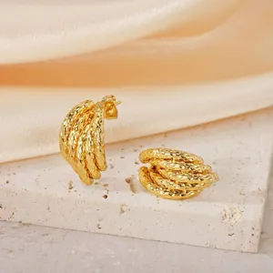 Vue détaillée de boucles d'oreilles géométriques dorées texturées sur pierre
