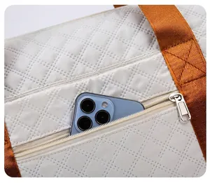 Détail de la poche arrière zippée d'un sac de voyage blanc matelassé avec smartphone