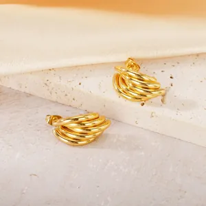 Détail rapproché de boucles d'oreilles géométriques en acier titane doré poli