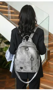 Detailed view of a grey vintage faux leather backpack worn by a model outdoors