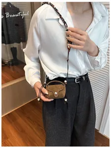 Close-up of a vintage brown suede mini crossbody bag worn by a model.