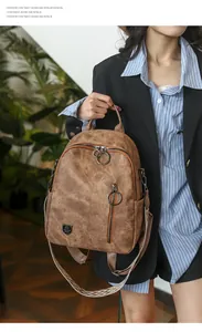 Detailed view of a vintage brown leather backpack with large ring zippers and strap.