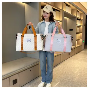 Mannequin asiatique tenant des sacs de voyage matelassés blanc et gris en showroom