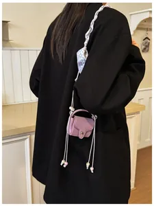 Detailed view of a mini purple coin purse worn as a stylish crossbody bag