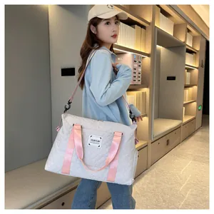 Grand sac de voyage avec sangles roses porté par une femme dans une bibliothèque