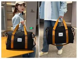 Sac de voyage noir matelassé à grande capacité avec des sangles orange porté par un modèle