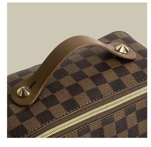 Nahaufnahme einer karierten Kosmetiktasche mit braunem Griff und goldenen Nieten