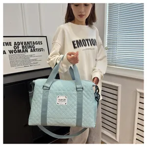 Sac de voyage matelassé bleu clair de grande capacité porté par un mannequin femme.