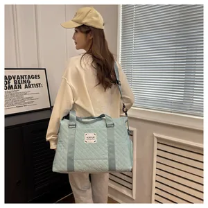 Sac de voyage matelassé bleu clair grande capacité porté à l'épaule par un mannequin