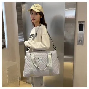 Grand sac de voyage gris matelassé pour femme porté à l'épaule dans un cadre moderne