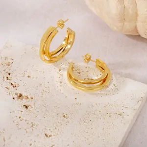 Vue détaillée de boucles d'oreilles créoles dorées en acier titane sur pierre