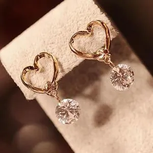 Detailed close-up of heart-shaped gold earrings with dangling round crystals