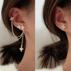 Detailed view of elegant gold star rhinestone ear cuff and stud earrings on ear.