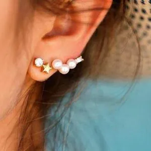 Detailed close-up of a fashion gold star and white pearl ear cuff stud on person