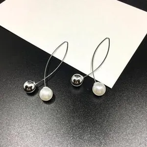 Close-up of minimalist silver wire earrings with pearl and metallic ball accents