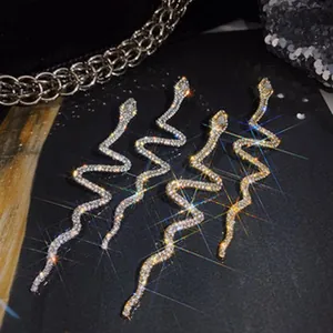 Close-up detail of glittering rhinestone-encrusted snake-shaped earrings in gold and silver