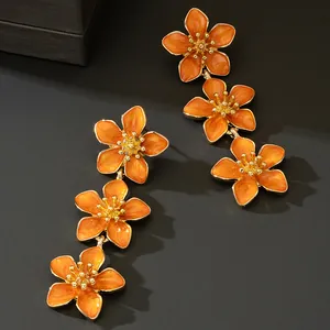 Detailed view of elegant triple orange enamel flower dangle earrings in gold finish