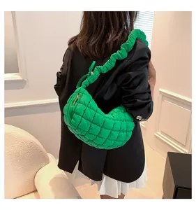 Stylish green quilted puffer crescent shoulder bag featuring a ruffled strap detail